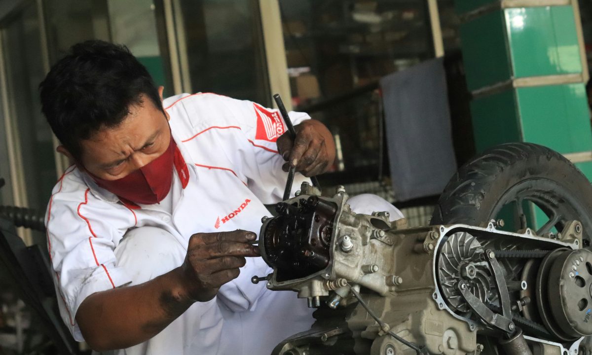 Teknisi bekerja di bengkel sebagai ilustrasi aktivitas ekonomi dan industri